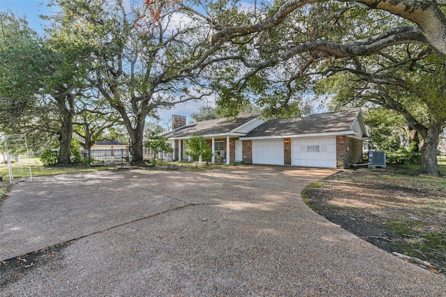 ranch-style house featuring central AC unit and a garage