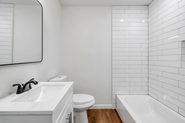 full bathroom with toilet, tiled shower / bath, vanity, and hardwood / wood-style floors