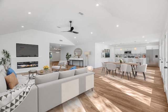 living room featuring vaulted ceiling, ceiling fan, and light hardwood / wood-style flooring