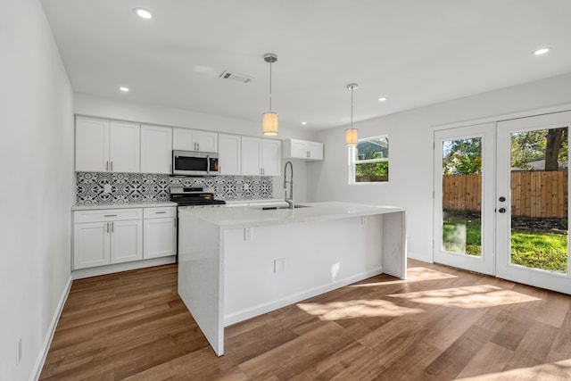 kitchen featuring white cabinetry, stainless steel appliances, sink, hardwood / wood-style flooring, and a center island with sink