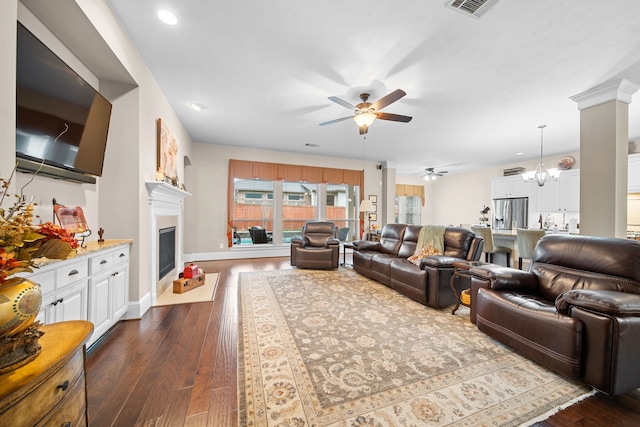 living room with dark hardwood / wood-style flooring, ceiling fan with notable chandelier, and decorative columns