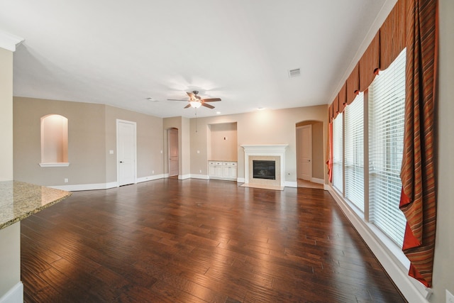 unfurnished living room featuring a fireplace with flush hearth, a ceiling fan, visible vents, baseboards, and dark wood-style floors
