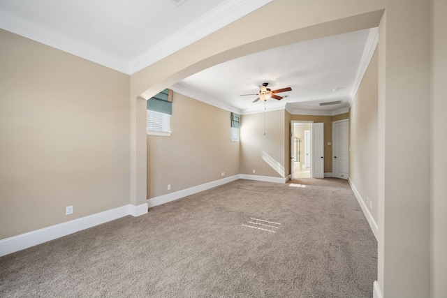 carpeted spare room with arched walkways, baseboards, ornamental molding, and ceiling fan