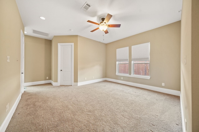 spare room featuring baseboards, light colored carpet, ceiling fan, and visible vents