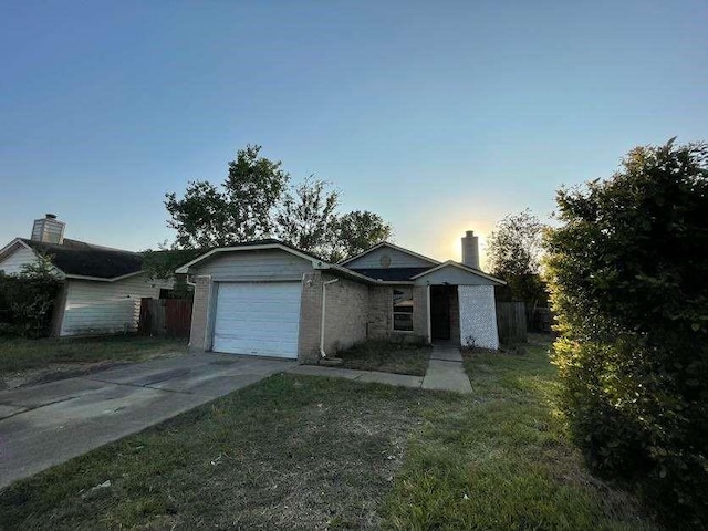 ranch-style house featuring a garage and a yard