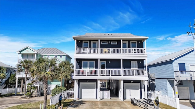 coastal inspired home with a garage, concrete driveway, and fence