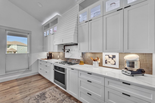 kitchen with vaulted ceiling, black electric stovetop, white cabinets, and oven