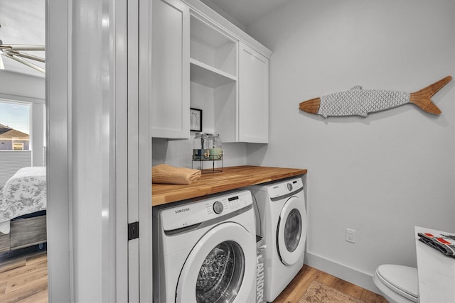 clothes washing area with light wood-type flooring, washer and dryer, baseboards, and a ceiling fan