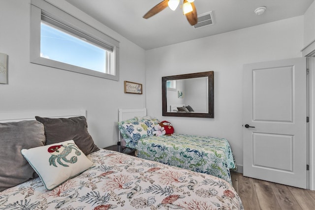 bedroom with wood finished floors, visible vents, and a ceiling fan