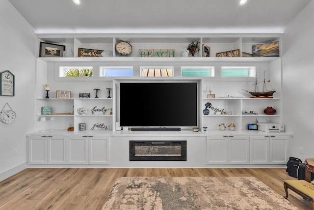 living room featuring light wood-style flooring and a glass covered fireplace