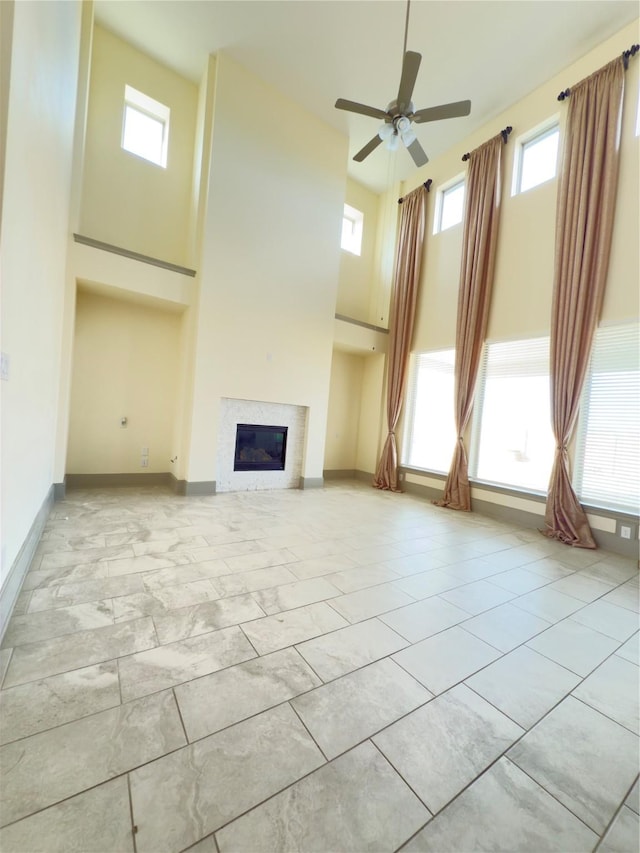 unfurnished living room featuring ceiling fan, a wealth of natural light, and a towering ceiling