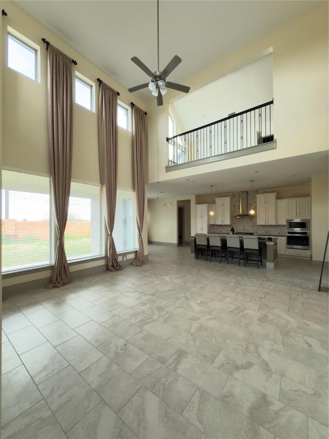 unfurnished living room with ceiling fan and a high ceiling