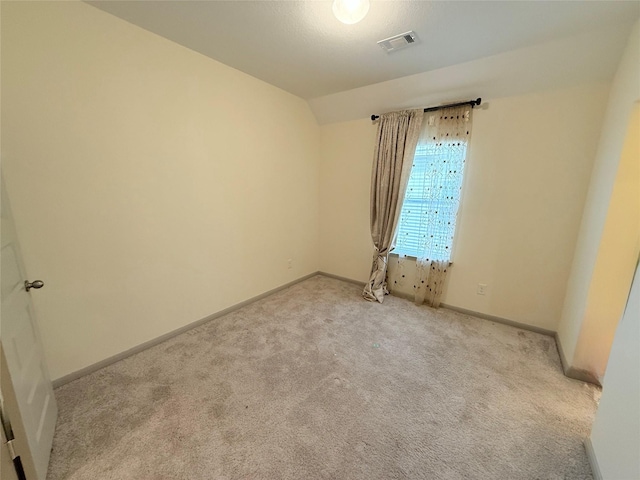 carpeted empty room with vaulted ceiling