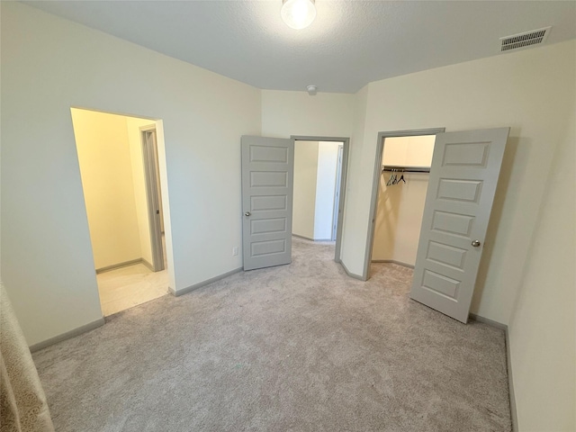 unfurnished bedroom with light carpet, a closet, and a spacious closet