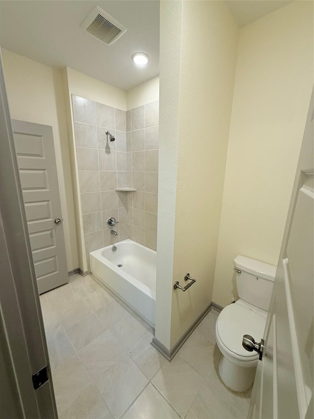 bathroom with toilet, tiled shower / bath combo, and tile patterned flooring