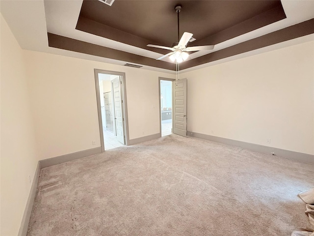 carpeted empty room with ceiling fan and a tray ceiling