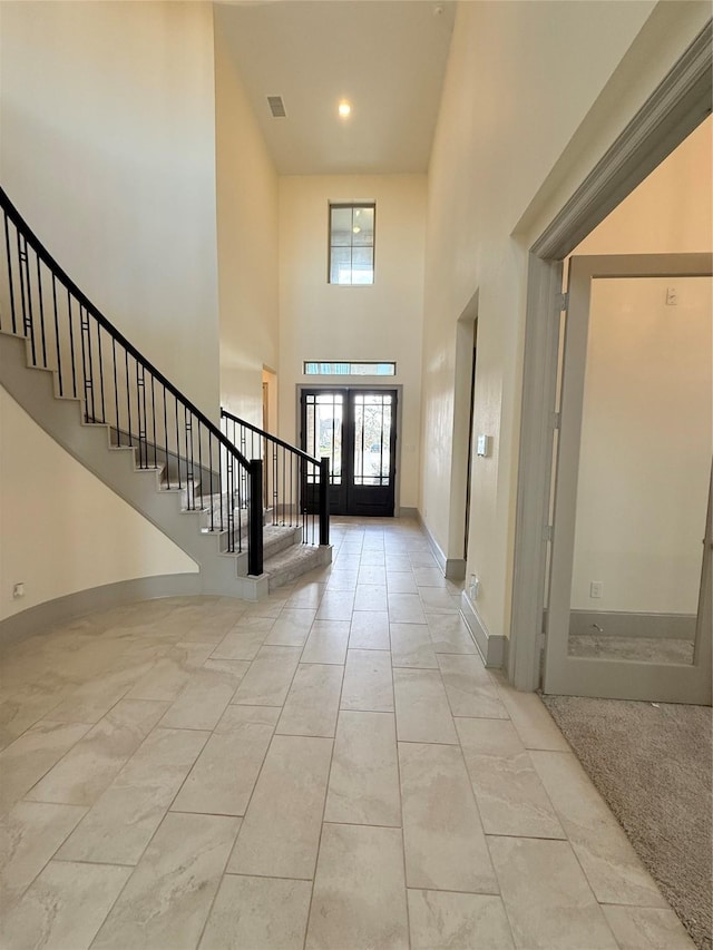 foyer featuring a towering ceiling and french doors