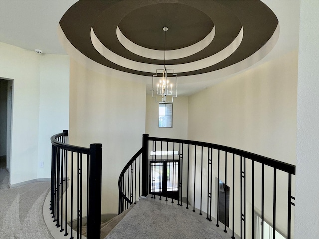 stairs featuring baseboards, a chandelier, carpet, and a tray ceiling