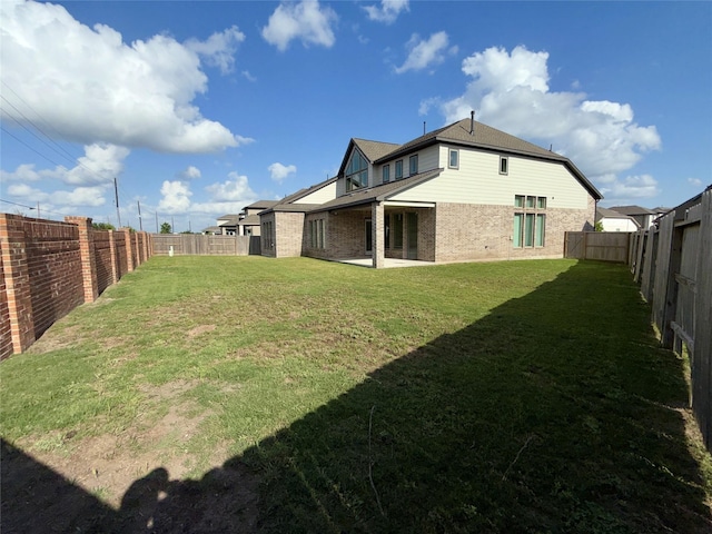 back of property featuring a yard, a fenced backyard, and brick siding