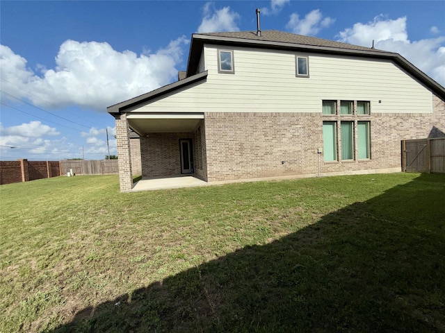 rear view of house with a patio, a lawn, a fenced backyard, and brick siding