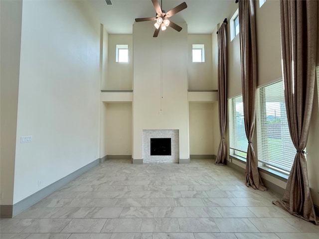 unfurnished living room with plenty of natural light, a high ceiling, ceiling fan, and a fireplace