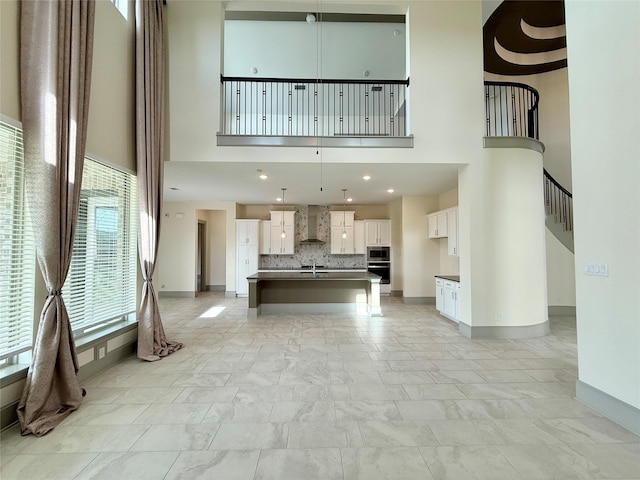 unfurnished living room with baseboards, stairs, and a high ceiling