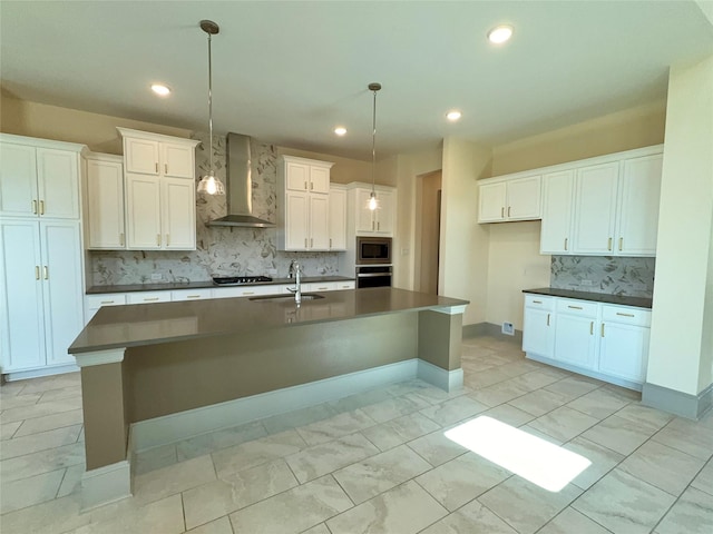 kitchen featuring wall chimney exhaust hood, a sink, appliances with stainless steel finishes, and dark countertops