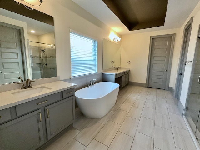bathroom with two vanities, a shower stall, a freestanding bath, and a sink