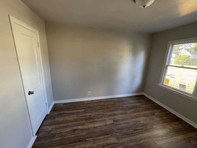 spare room featuring dark wood-type flooring and baseboards