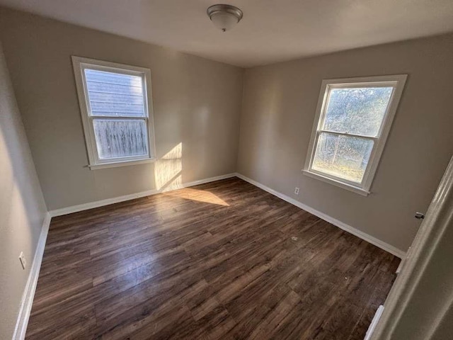 empty room featuring baseboards and dark wood finished floors