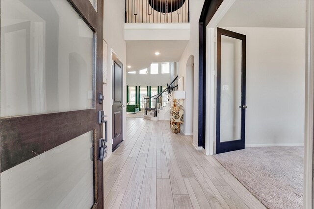 entryway featuring french doors, a towering ceiling, and light wood-type flooring