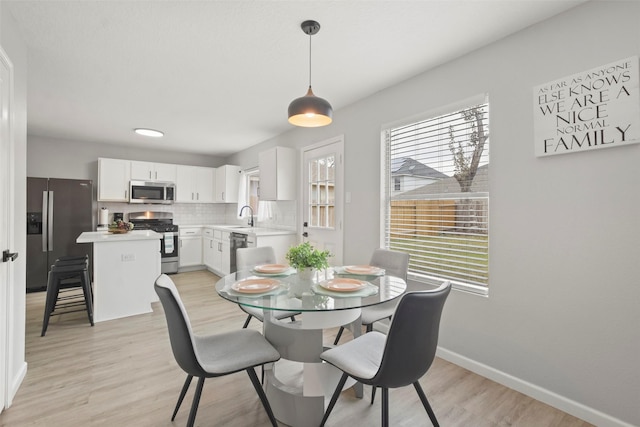 dining space with light hardwood / wood-style flooring and sink