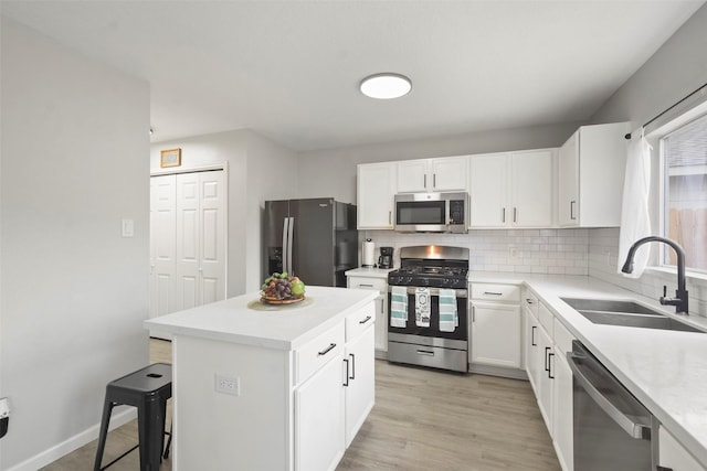 kitchen with a kitchen island, decorative backsplash, sink, white cabinetry, and appliances with stainless steel finishes