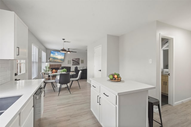 kitchen featuring ceiling fan, tasteful backsplash, dishwasher, white cabinets, and light hardwood / wood-style flooring