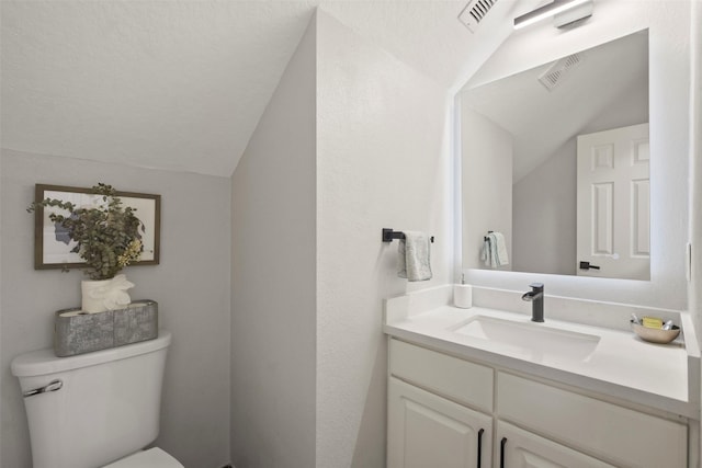 bathroom with toilet, vanity, and vaulted ceiling