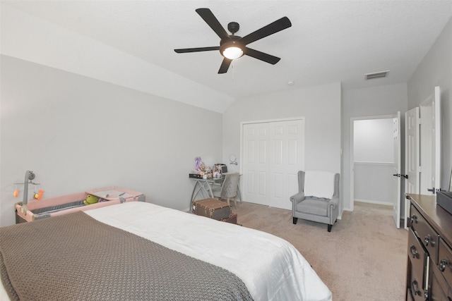 carpeted bedroom with ceiling fan, a closet, and vaulted ceiling