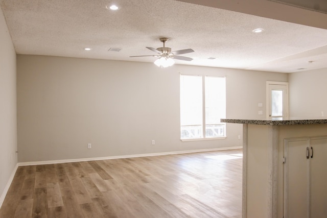 interior space featuring ceiling fan, a textured ceiling, and light hardwood / wood-style flooring