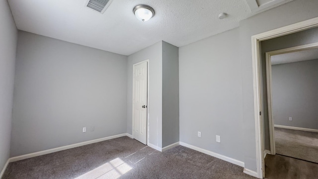 unfurnished bedroom featuring a textured ceiling, a closet, and dark carpet