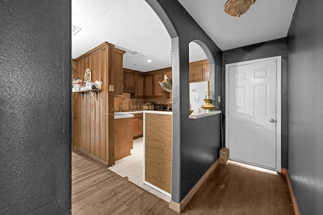 kitchen featuring a textured ceiling, extractor fan, light hardwood / wood-style flooring, and sink