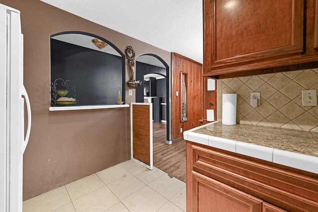 kitchen featuring a textured ceiling, light tile patterned flooring, and backsplash