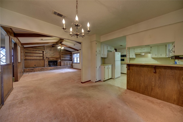 kitchen featuring kitchen peninsula, decorative light fixtures, a fireplace, vaulted ceiling with beams, and white refrigerator