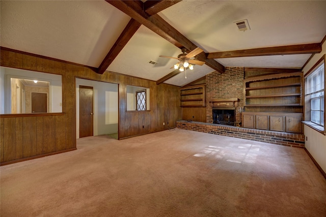 unfurnished living room featuring ceiling fan, vaulted ceiling with beams, a brick fireplace, and wooden walls