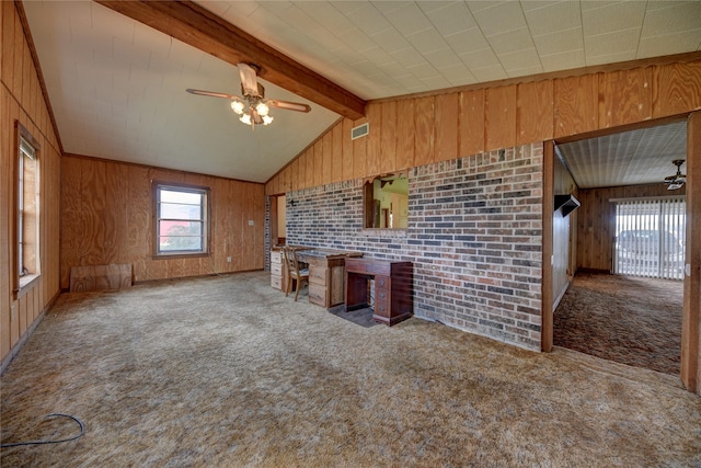 unfurnished living room featuring vaulted ceiling with beams, brick wall, carpet floors, and wooden walls