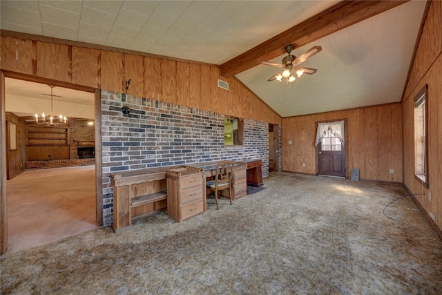 kitchen with wooden walls, a brick fireplace, brick wall, light colored carpet, and ceiling fan with notable chandelier