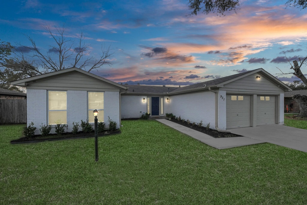 ranch-style home featuring a garage and a lawn