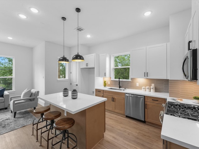 kitchen featuring white cabinetry, sink, dishwasher, pendant lighting, and a center island