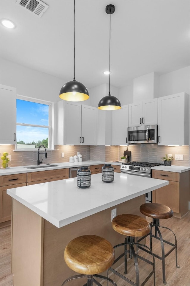 kitchen featuring sink, white cabinetry, appliances with stainless steel finishes, and a center island