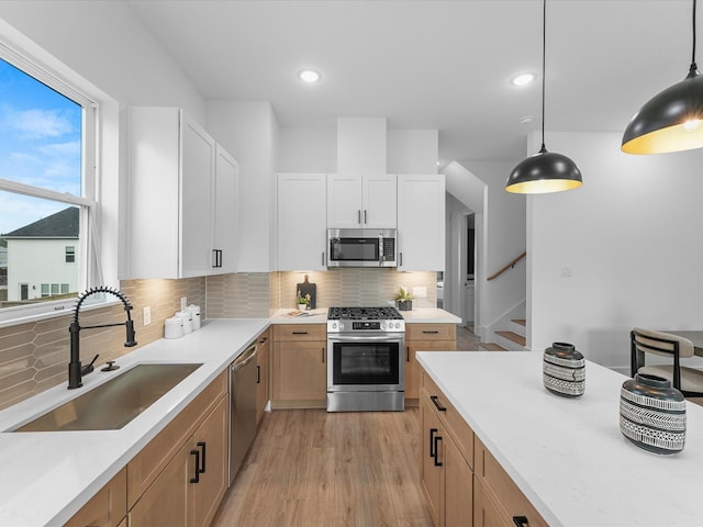 kitchen with decorative light fixtures, appliances with stainless steel finishes, sink, and white cabinetry