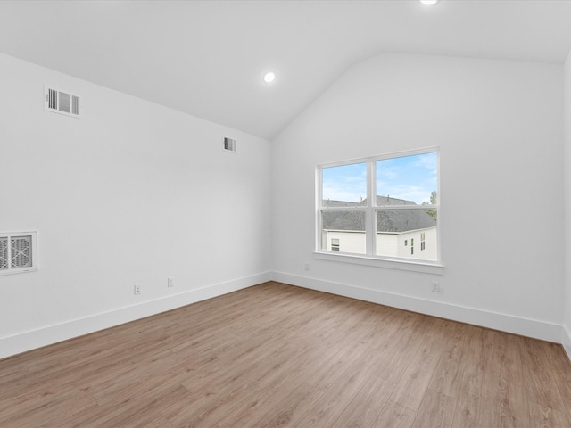 spare room featuring light hardwood / wood-style floors and vaulted ceiling