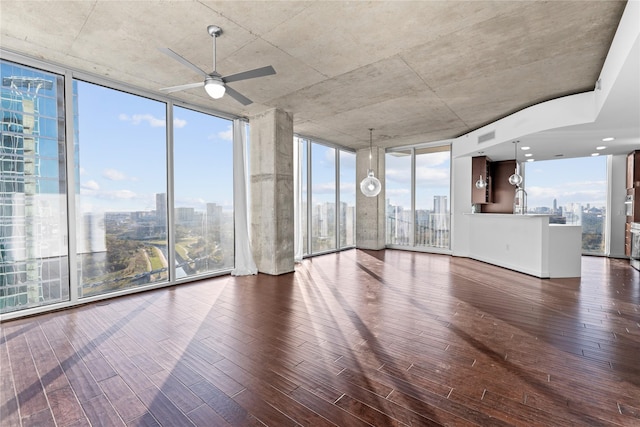 unfurnished living room featuring plenty of natural light, a wall of windows, and dark hardwood / wood-style flooring